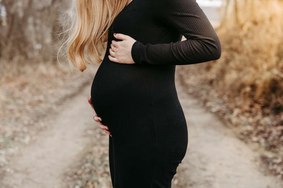 Babybauch im schwarzen Kleid auf einem Feldweg