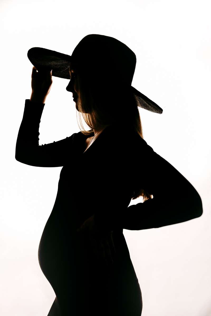 Silhouette einer Schwangeren mit Hut vor hellem Hintergrund