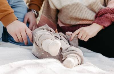 Eltern legen ihre H&auml;nde um ihr in eine Decke gewickeltes Baby
