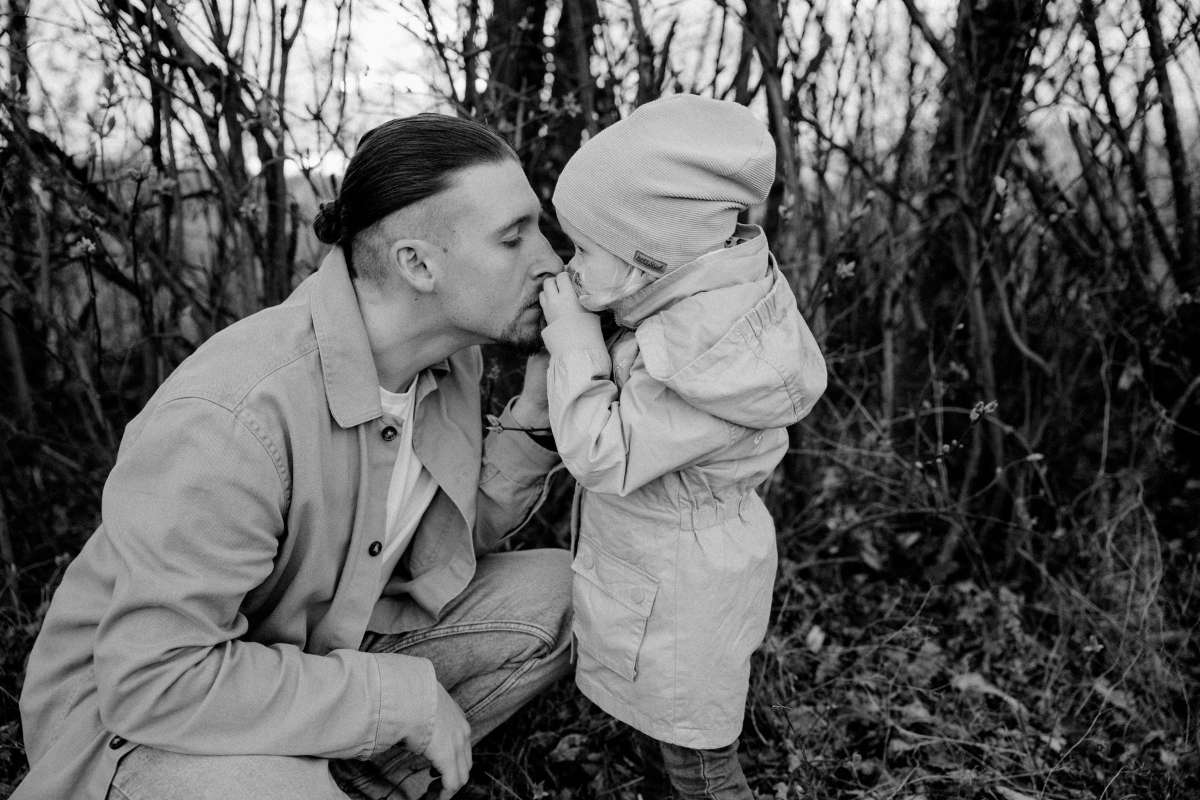 Schwarzwei&szlig;: Vater gibt seinem Kind drau&szlig;en einen Kuss