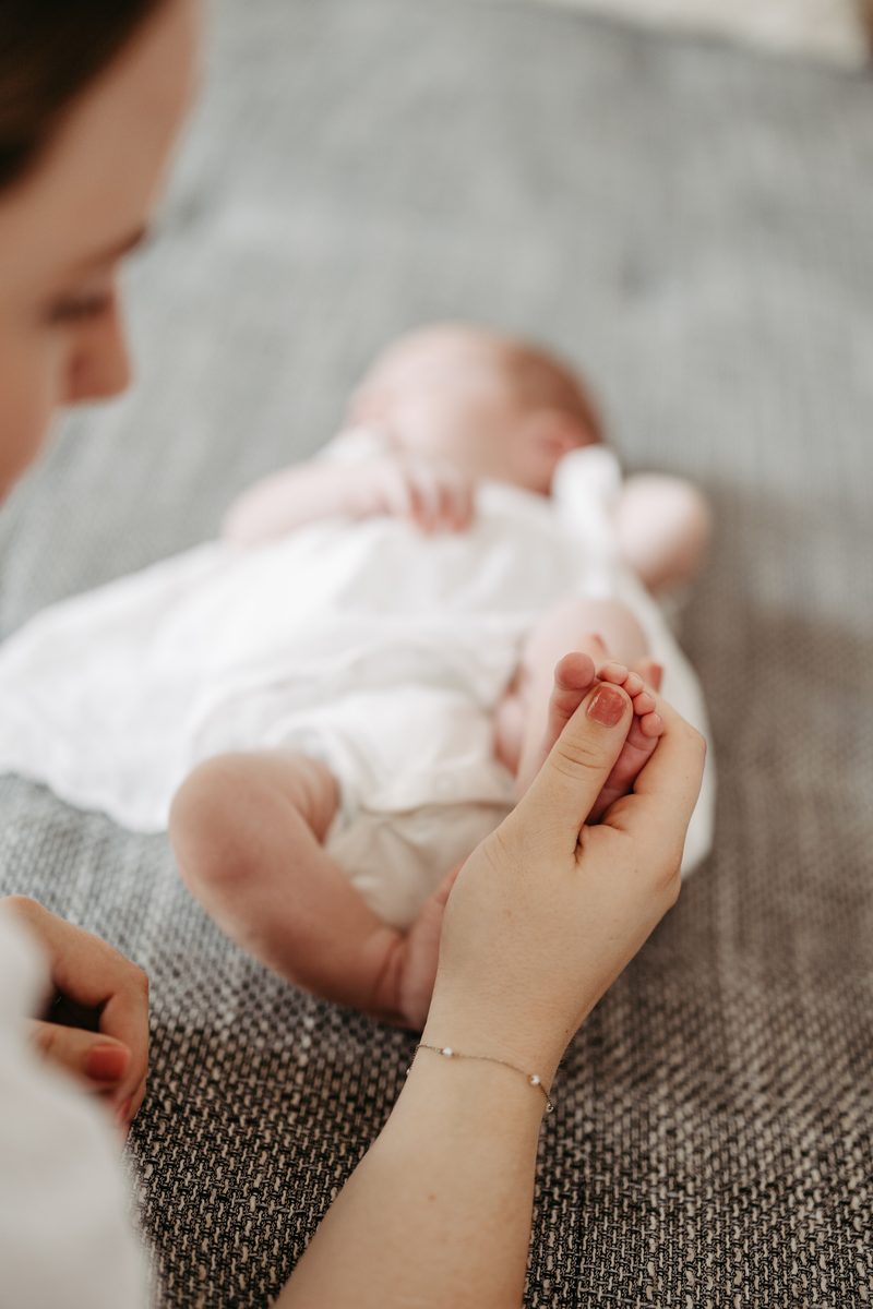 Mutter h&auml;lt den Fu&szlig; ihres schlafenden Neugeborenen
